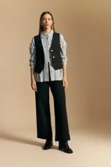 Camisa de manga larga con diseño de rayas verticales en tonos grises y blancos, cuello camisero y cierre frontal con botones.