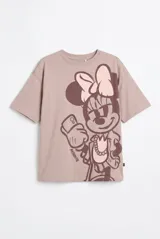 Remera de manga corta color gris topo con diseño oversize, cuello redondo y estampado grande de Minnie Mouse tomándose una selfie en tonos marrón oscuro y rosado.