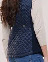 Chaleco acolchado de diseño entallado color beige, con matelaseado en patrón de rombos en frente y espalda, cuello alto estructurado y cierre frontal completo con cremallera metálica y ribete a contraste.