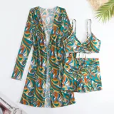 Conjunto de traje de baño de tres piezas con estampado de hojas tropicales en tonos blanco y negro. Incluye un top tipo tankini con cordón ajustable en el centro, un short de tiro alto y una camisa abierta de manga larga tipo salida de baño.