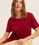 Vestido corto marrón oscuro, estilo camiseta, con escote redondo, mangas cortas y bolsillos laterales. El bajo es redondeado.