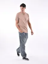 Remera de manga corta color beige, con cuello tipo henley con dos botones frontales y textura de tejido fino.
