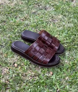 Sandalias bajas de cuero color dorado, con tiras tejidas en la parte superior y suela marrón.