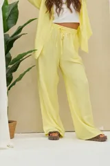 Pantalón de pierna ancha color amarillo pastel, de tiro medio con cintura elástica fruncida y cordón ajustable.