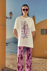 Remera color beige con estampado de un pescado y la frase "Sardine Club" en color lila.