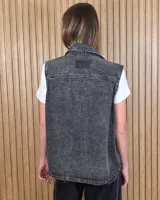 Chaleco de denim 100% algodón en color negro gastado, con cuello camisero, cierre frontal de botones metálicos y bolsillos delanteros con solapa.