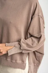 Sweater de algodón peinado con efecto lavado, de corte oversize, cuello redondo y mangas largas con costuras visibles.