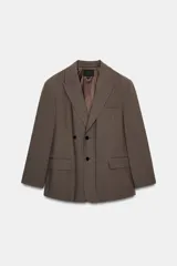 Blazer oversize de Zara con diseño a rayas verticales, cuello con solapa de muesca y hombreras. Presenta un cierre frontal cruzado con doble botonadura, bolsillos delanteros con solapa y un bolsillo de vivo en el pecho. Incluye forro interior a tono.