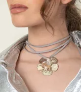 Collar con dije dorado en forma de flor con incrustaciones de perlas, con tiras de cuero sintético color beige que se atan al cuello.