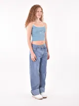 Musculosa corta color celeste, con tirantes finos blancos y ribete blanco en el escote. Presenta un pequeño bordado de un girasol en el frente.