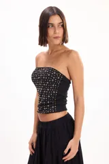 Top strapless negro de corte ajustado, con diseño estampado de pequeños círculos y rombos dorados y plateados.