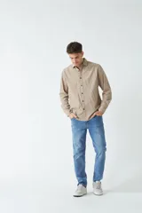 Camisa de pana color beige, de corte regular, con cuello clásico y cierre frontal con botones. Confeccionada en algodón.