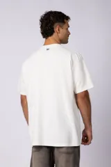 Remera de corte oversized en color marrón, confeccionada en tejido de algodón con textura de micropanal. Presenta cuello redondo con detalle de costura en forma de X y mangas cortas de estilo caído.