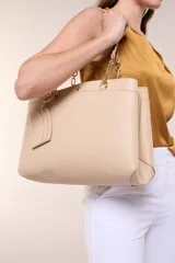 Cartera de hombro de cuero sintético beige, con estructura tripartita de compartimento central con cierre y dos compartimentos laterales con broche magnético. Posee asas dobles con detalles de cadena metálica dorada y un tarjetero independiente desmontable.