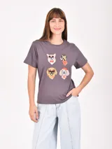 Remera lila de corte recto y mangas cortas, con estampado pequeño de un gato blanco con gorro rojo, gafas de sol y copa de vino, junto a la frase 'J'adore'.