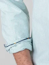 Camisa celeste de corte clásico, con cuello abotonado, manga larga y logo bordado en el pecho.