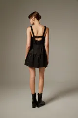 Vestido corto de poliéster color negro con estampado de lunares brillantes tipo strass, tirantes finos con volados, escote con abertura cut-out en el centro y falda con volado fruncido en el borde inferior.