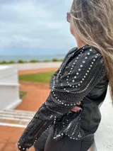 Chaqueta negra de cuero sintético con tachas plateadas, lentejuelas y strass.