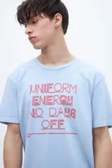 Remera celeste con estampa frontal en color rojo con la frase "UNIFORM ENERGY NO DAYS OFF".