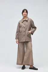 Chaquetón de lana fina sin teñir, con cuello camisero, cierre frontal de botones y bolsillos delanteros. Diseño de corte recto y estructura clásica.