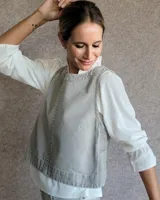 Chaleco de corte recto y largo a la cintura, confeccionado en denim con estampado de rayas verticales en tonos azul y blanco. Presenta cuello redondo y costuras visibles que definen su estructura.