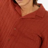 Camisa de manga corta color ladrillo con tejido calado, cuello clásico y cierre frontal con botones.