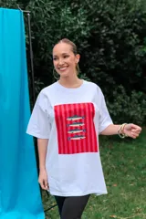 Remerón de algodón blanco con corte oversize y cuello redondo, que presenta un estampado frontal con diseño de una lata de sardinas sobre fondo de rayas.