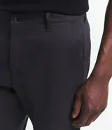 Pantalón de vestir para hombre, color beige claro, de corte slim y sastrería. Presenta cierre frontal con botón y cremallera, y bolsillos laterales y traseros.