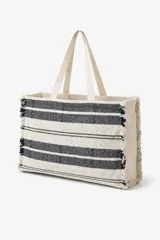 Bolso tote tejido a mano con diseño de rayas horizontales en blanco y negro, y detalles en zigzag. Los bordes laterales tienen flecos. Cuenta con dos asas de tela color crema.