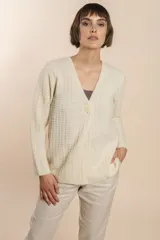 Cardigan tejido con efecto fantasia color crema. Una prenda de silueta amplia y cómoda. Tejido en 100% lana fina sin teñir.