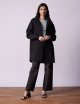 Gabardina negra impermeable de poliéster, con capucha desmontable, cierre central con cremallera y botones a presión, bolsillos delanteros y forro interno. Marca Weatherproof.