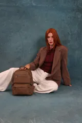 Mochila de cuero sintético color negro con textura granulada. Cuenta con un compartimento principal con cierre, un bolsillo frontal con cierre, correas ajustables y asa superior.