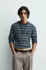 Camiseta de manga larga con cuello redondo, confeccionada en tejido acanalado de algodón con rayas horizontales en tonos azul marino, verde y gris claro.