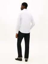 Camisa blanca de corte regular de Tommy Hilfiger, confeccionada en puro algodón regenerativo con diseño de raya diplomática y sutil textura diagonal. Presenta cuello camisero, cierre frontal de botones y el logo de la marca bordado en el pecho.