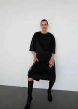 Top de corte recto confeccionado en tejido mezcla de lana, con cuello redondo y mangas tres cuartos. Presenta un diseño minimalista con cierre de cremallera en la parte posterior.