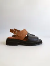 Sandalias de cuero color negro y marrón con textura tipo cocodrilo, con hebilla ajustable y suela track. Fabricadas en Uruguay.