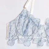 Conjunto de lencería de encaje celeste compuesto por soutiene con varillas, bombacha colaless, porta ligas y ligas para las piernas.