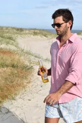 Camisa rosa de manga larga con cuello clásico y cierre abotonado.