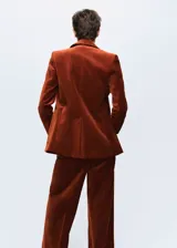 Blazer de terciopelo color marrón, con solapas de muesca, cierre frontal de un botón y dos bolsillos de parche delanteros.