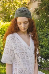 Vestido corto color blanco, tejido calado tipo encaje de algodón, corte recto y suelto, con mangas cortas, botonadura frontal forrada y escote en V.