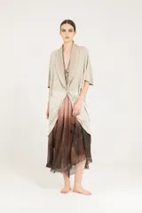 Blazer de lino color beige, de corte holgado y estilo kimono, con mangas cortas caídas, cuello chal, un botón de cierre y bolsillos frontales.