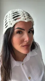 Gorro tipo turbante de tejido crochet color crudo, con diseño calado y lentejuelas plateadas.