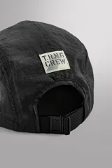 Gorra deportiva de estilo técnico confeccionada en tejido ripstop ligero, con estructura de cinco paneles y visera curva. Presenta el logo bordado en el panel frontal y ojales de ventilación laterales.