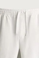 Bermuda regular fit de tejido elástico color blanco, con cintura elástica ajustable mediante cordón, bolsillos delanteros y bolsillos traseros de vivo.