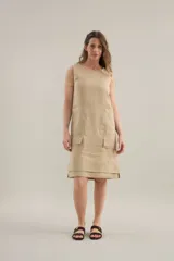 Vestido midi de lino color beige, de silueta relajada, escote redondo, sisas amplias y bolsillos delanteros aplicados.
