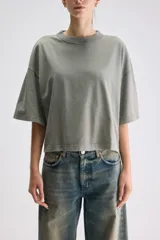 Remera crop de calce relajado color verde militar con efecto lavado, cuello redondo ribeteado, hombros caídos y mangas cortas amplias.