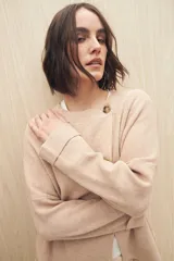 Sweater color beige de tejido de punto con cruce irregular y botones a contraste.