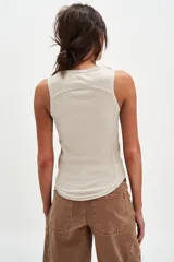 Musculosa de algodón acanalado color blanco off-white, de calce ajustado, con escote redondo, ruedo curvo y tiras con hebillas metálicas decorativas en los hombros.