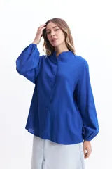 Camisa de manga larga color blanco, con cuello mao y corte holgado. Confeccionada en tejido tipo lino.