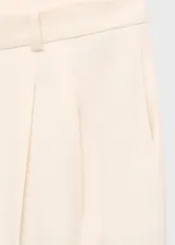 Pantalón de tiro medio color marfil, de diseño recto y largo, con pinzas frontales y bolsillos laterales.